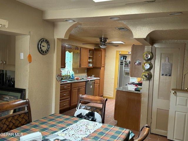 kitchen featuring ceiling fan, stainless steel dishwasher, white refrigerator with ice dispenser, a textured ceiling, and dark tile patterned flooring