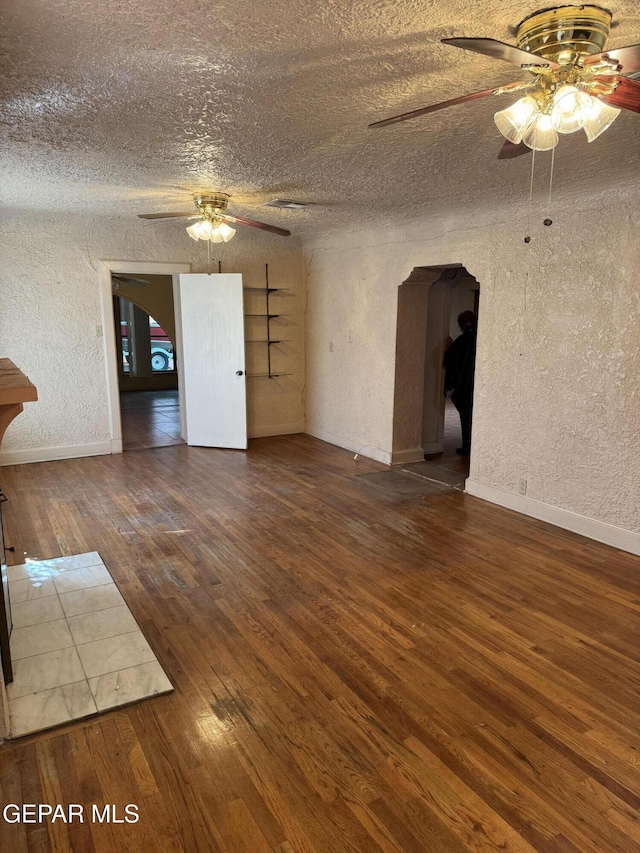 spare room with a textured ceiling, dark hardwood / wood-style flooring, and ceiling fan