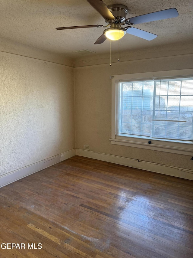 spare room with a textured ceiling, dark hardwood / wood-style floors, and a wealth of natural light