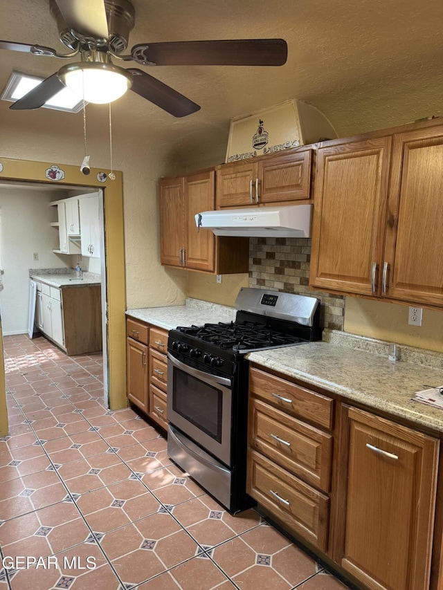 kitchen with ceiling fan, stainless steel gas range oven, light tile patterned floors, and tasteful backsplash