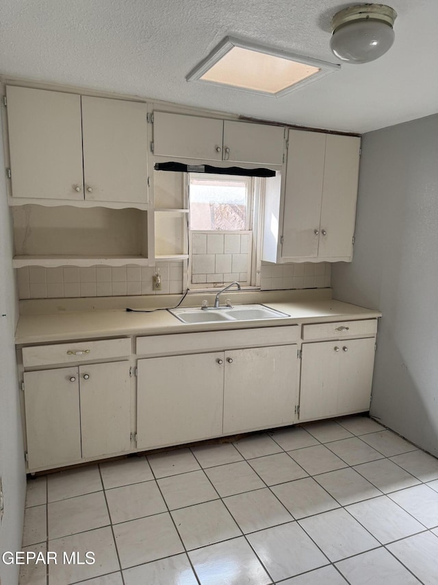 kitchen featuring white cabinets, sink, light tile patterned floors, and backsplash