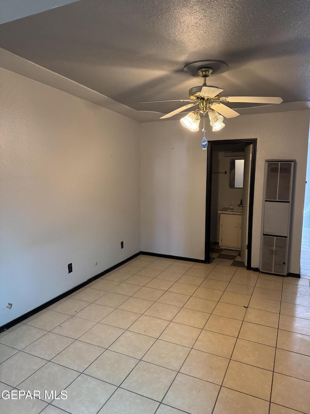 empty room featuring a textured ceiling, ceiling fan, and light tile patterned flooring