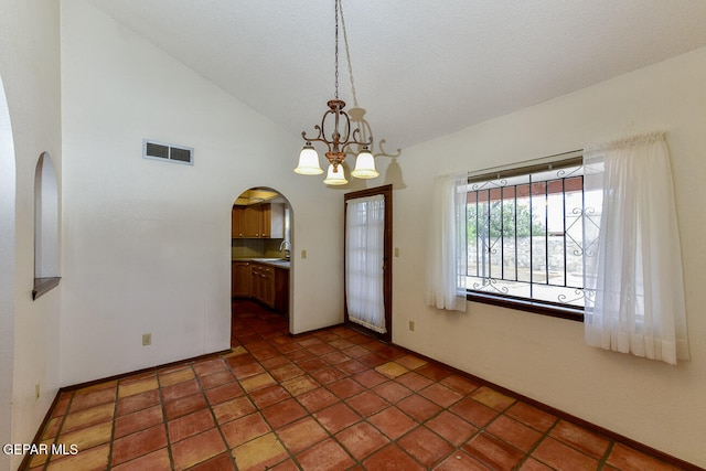 interior space with sink, dark tile patterned floors, a textured ceiling, high vaulted ceiling, and a notable chandelier