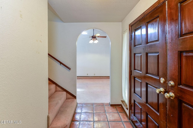 entrance foyer featuring a textured ceiling, light carpet, and ceiling fan