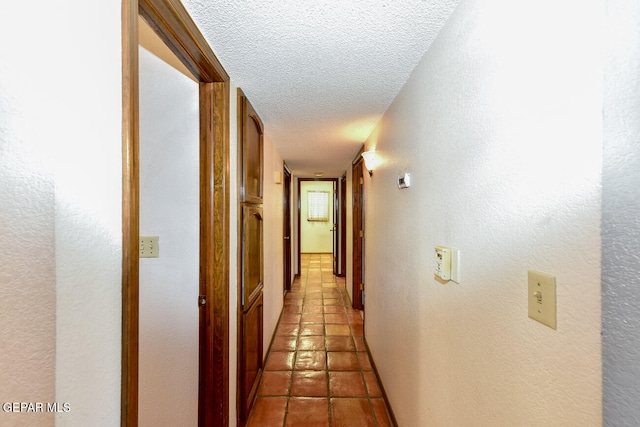 hallway featuring a textured ceiling and light tile patterned floors