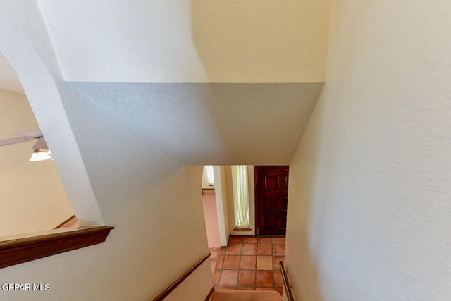 stairway with ceiling fan and tile patterned flooring