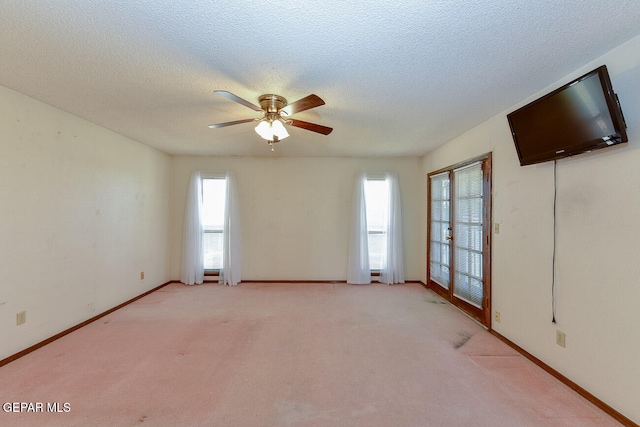 spare room featuring a textured ceiling, light carpet, and ceiling fan