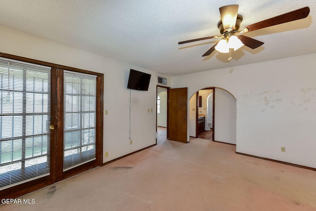 carpeted spare room with a wealth of natural light, a textured ceiling, and ceiling fan