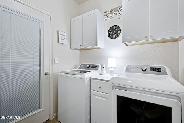 clothes washing area featuring cabinets and washer and dryer