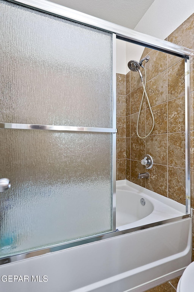 bathroom with enclosed tub / shower combo, tile patterned floors, and toilet