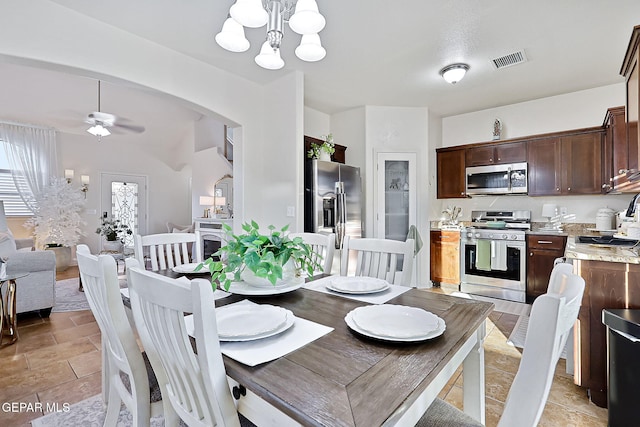 dining space featuring ceiling fan with notable chandelier