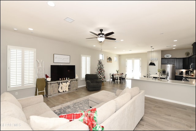 living room with hardwood / wood-style floors, ceiling fan, and sink