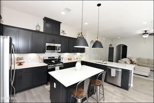 kitchen with a kitchen breakfast bar, tasteful backsplash, pendant lighting, and appliances with stainless steel finishes