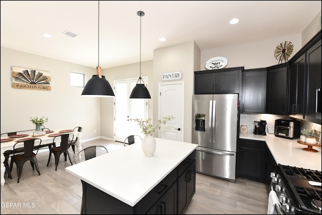 kitchen featuring decorative backsplash, stainless steel appliances, pendant lighting, light hardwood / wood-style floors, and a kitchen island