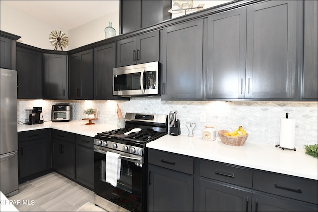 kitchen with stainless steel appliances, light hardwood / wood-style flooring, and tasteful backsplash