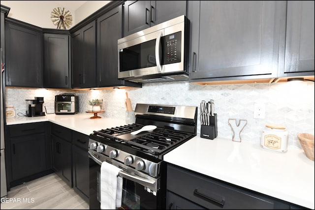 kitchen featuring light wood-type flooring, backsplash, and appliances with stainless steel finishes