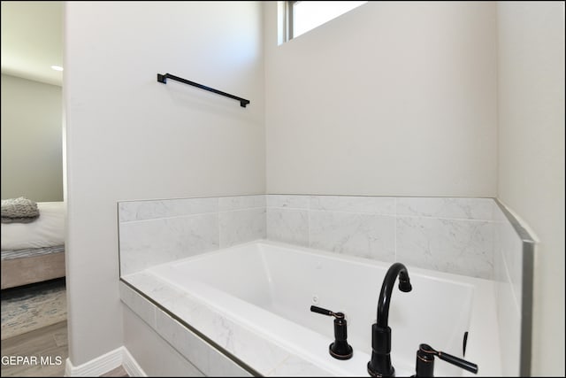 bathroom with hardwood / wood-style floors and a relaxing tiled tub