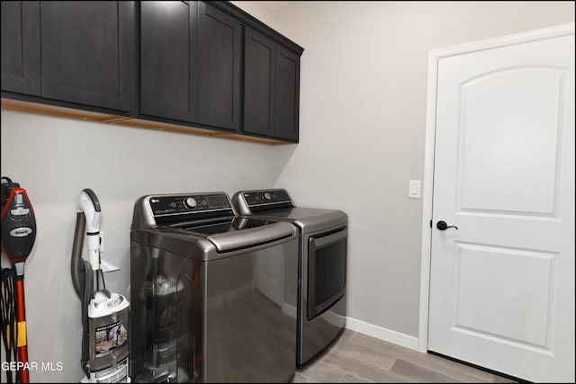 washroom with cabinets, light hardwood / wood-style floors, and washing machine and clothes dryer