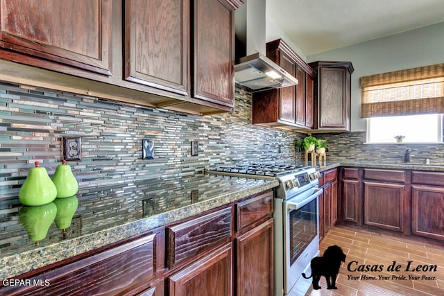 kitchen featuring stone countertops, backsplash, light hardwood / wood-style flooring, wall chimney range hood, and high end range