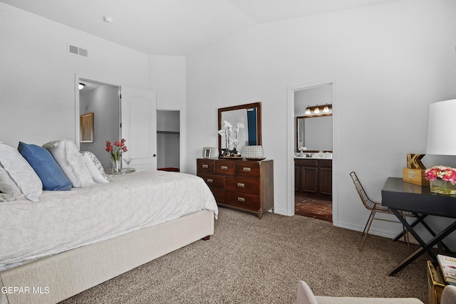carpeted bedroom with connected bathroom, visible vents, and lofted ceiling