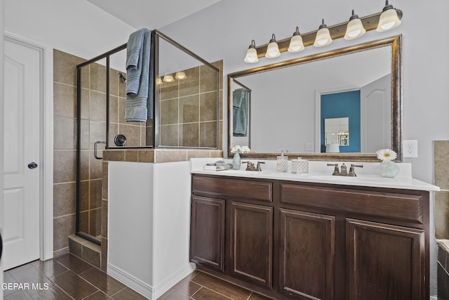 full bathroom with a stall shower, double vanity, and a sink