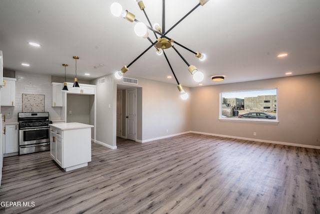 kitchen with stainless steel range with gas stovetop, white cabinetry, light wood-type flooring, and a center island