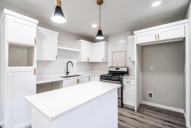 kitchen with stainless steel gas range, white cabinetry, sink, and pendant lighting