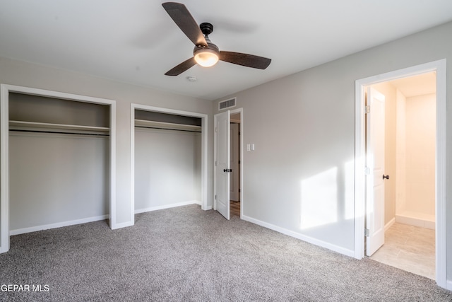 unfurnished bedroom with light colored carpet, ceiling fan, and two closets