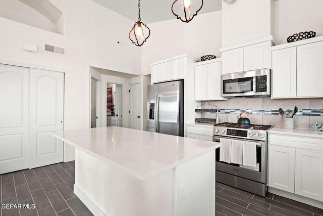 kitchen with high vaulted ceiling, white cabinetry, and stainless steel appliances