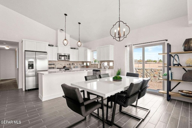 dining area featuring high vaulted ceiling and an inviting chandelier