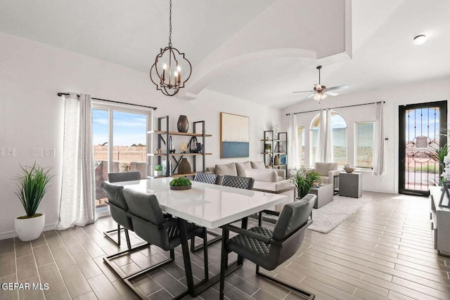 dining area featuring ceiling fan with notable chandelier, hardwood / wood-style flooring, and vaulted ceiling