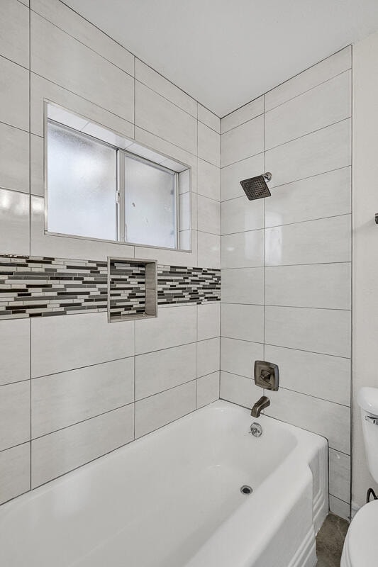 bathroom featuring toilet and tiled shower / bath