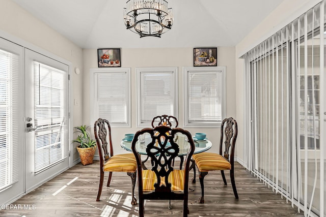 dining room featuring hardwood / wood-style floors, vaulted ceiling, and a notable chandelier