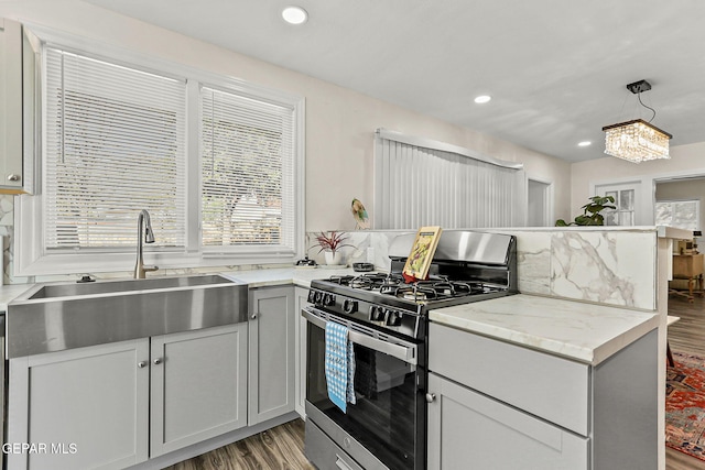 kitchen with hardwood / wood-style floors, sink, hanging light fixtures, gray cabinets, and gas stove