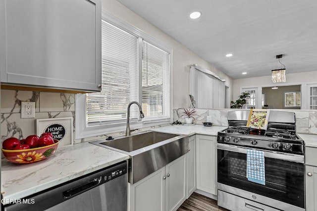 kitchen with white cabinets, sink, hanging light fixtures, a notable chandelier, and stainless steel appliances