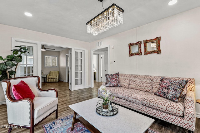 living room with ceiling fan with notable chandelier and dark wood-type flooring