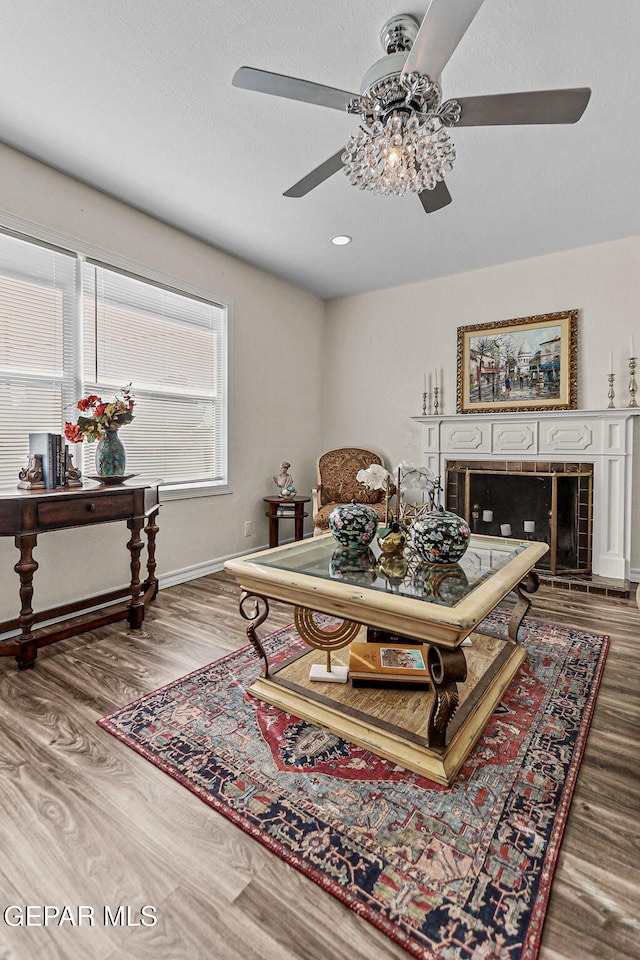 living room with ceiling fan, a fireplace, and hardwood / wood-style flooring