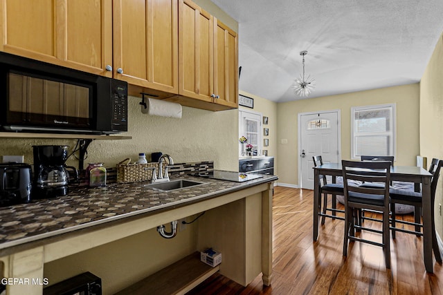 kitchen featuring dark hardwood / wood-style flooring, an inviting chandelier, stovetop, and sink