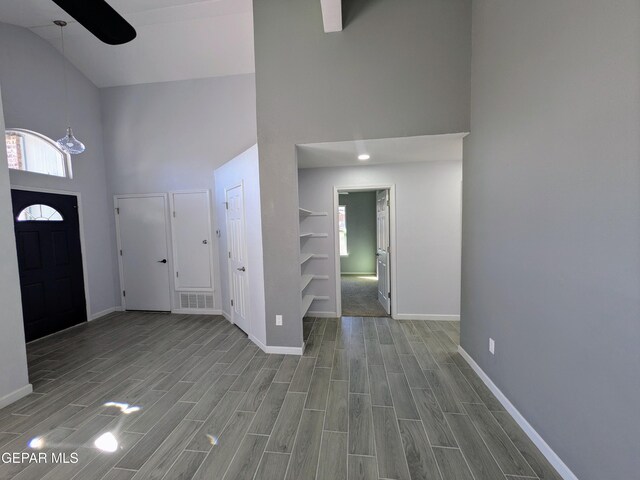 foyer entrance with high vaulted ceiling and ceiling fan with notable chandelier