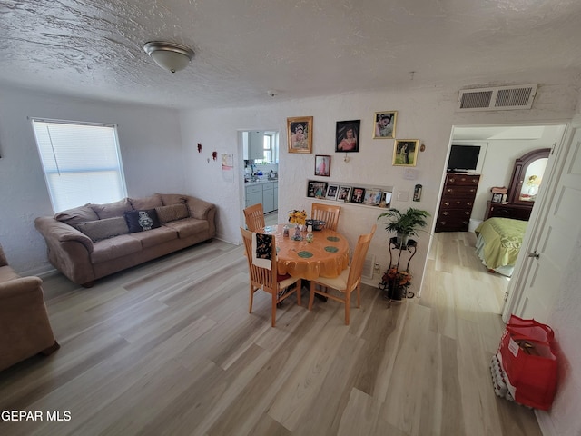 dining room featuring a textured ceiling and light hardwood / wood-style floors