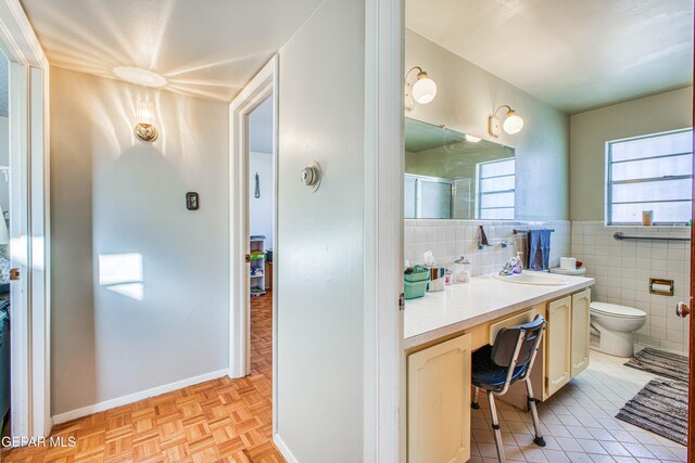 bathroom with tile walls, vanity, an enclosed shower, toilet, and parquet flooring