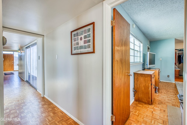 corridor with a textured ceiling and light parquet floors