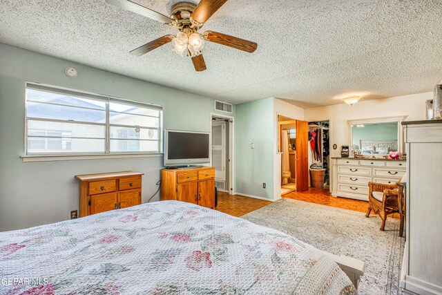 bedroom featuring a textured ceiling, a spacious closet, ceiling fan, and a closet