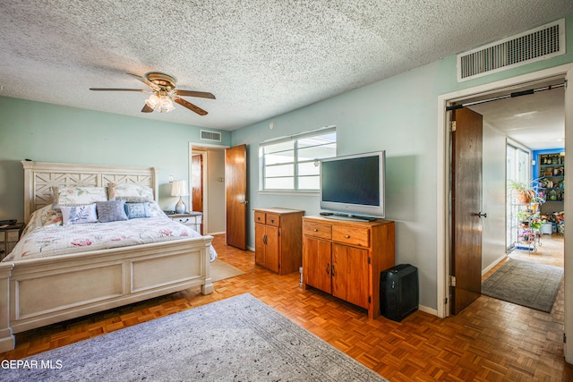 bedroom featuring a textured ceiling, ceiling fan, and light parquet floors