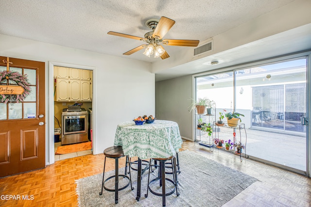 dining room featuring light parquet flooring, a textured ceiling, ceiling fan, and washer / dryer