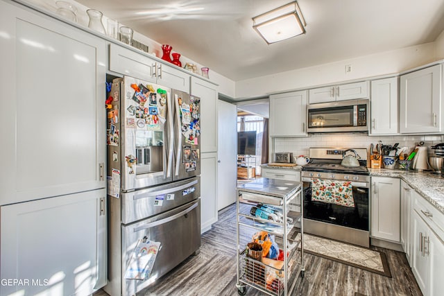 kitchen with dark hardwood / wood-style floors, white cabinetry, appliances with stainless steel finishes, and tasteful backsplash