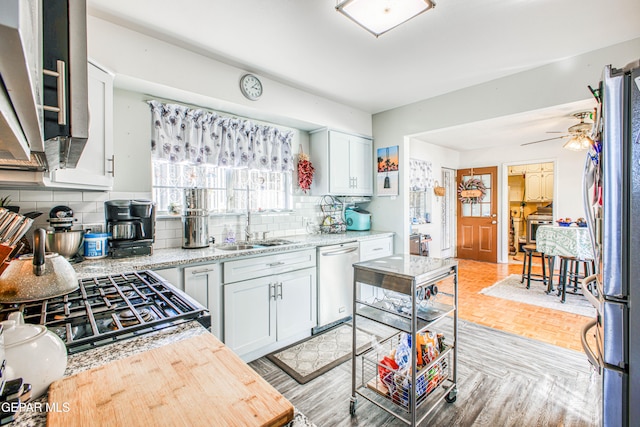 kitchen featuring stainless steel appliances, sink, backsplash, and light hardwood / wood-style flooring