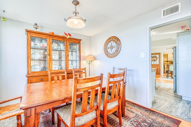 dining area with a textured ceiling and hardwood / wood-style flooring