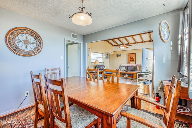 dining area with ceiling fan, a textured ceiling, and lofted ceiling with beams