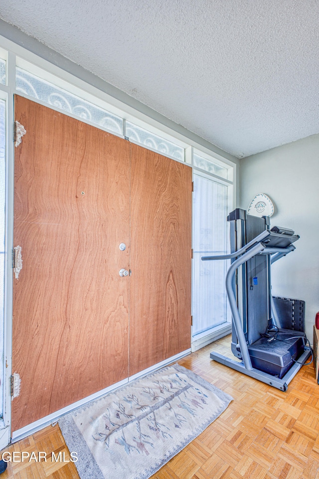 workout area with a textured ceiling and light parquet floors